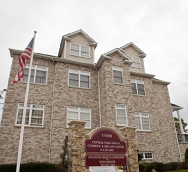 The image shows a two-story building with a brick facade, a flag on a pole, and a sign indicating  Central Park Brick . There are multiple windows visible on both floors of the building.