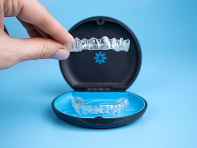 An open display case with a clear lid showcasing a set of transparent dental aligners.