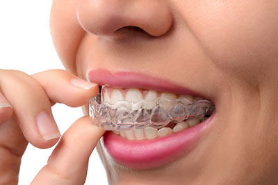 An adult female hand holding a toothbrush with bristles against her mouth, showcasing dental hygiene.