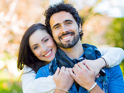 The image shows a man and a woman embracing each other with smiles on their faces, suggesting a close relationship between them.