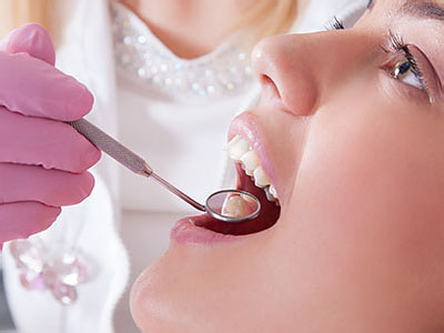 The image shows a dental professional performing a cleaning procedure on a patient s teeth using specialized equipment.