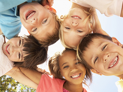 This image shows a group of children smiling at the camera with their arms around each other s shoulders, suggesting a moment of joy and camaraderie.