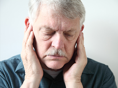 The image shows an elderly man with his hand on his face, appearing to be asleep or resting, with a neutral background.